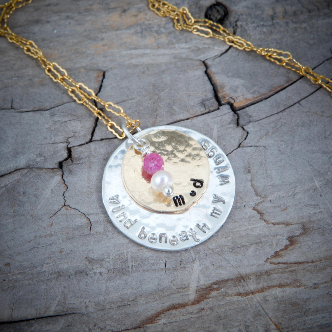 double disk gold and silver message pendant on wood background
