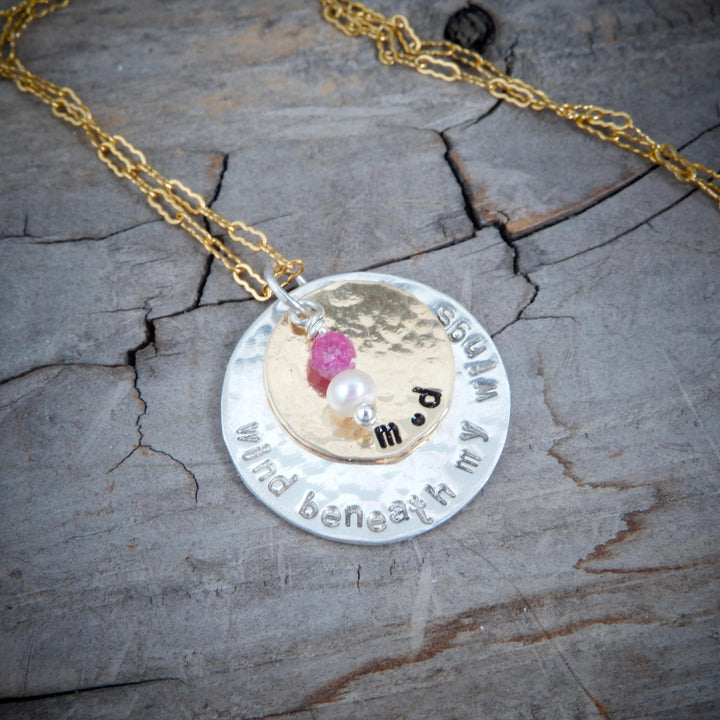 double disk gold and silver message pendant on wood background