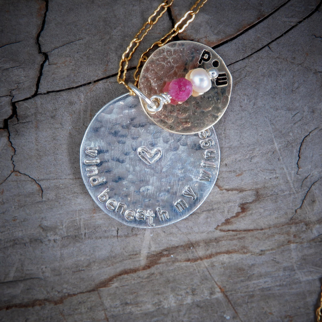 double disk gold and silver message pendant on wood background