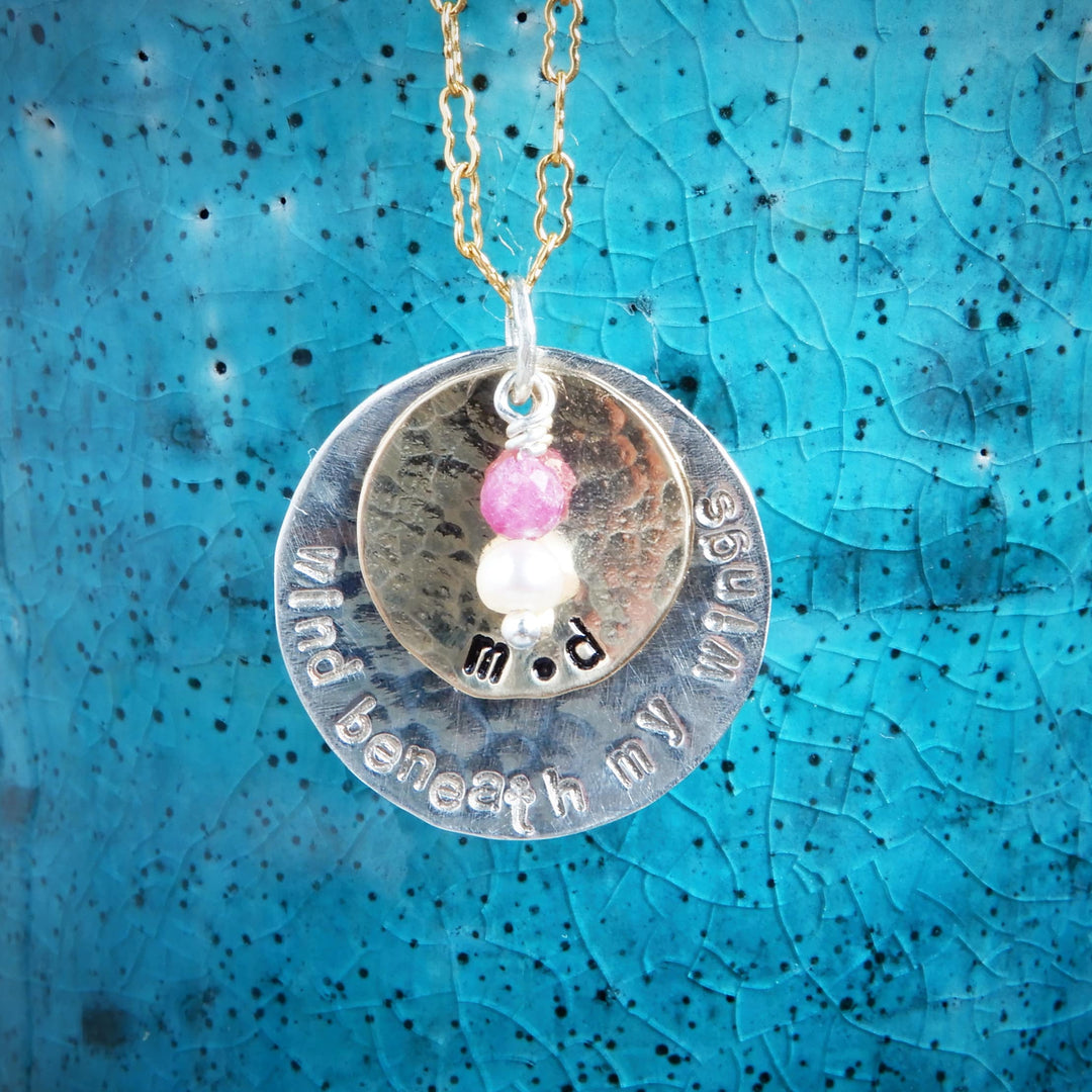 double disk gold and silver message pendant on blue background