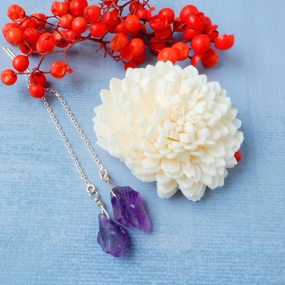 raw amethyst silver threader earrings on blue background with flowers