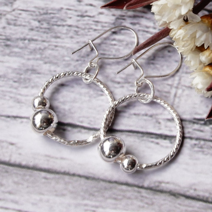 silver sensory fidget hoop earrings on wood background