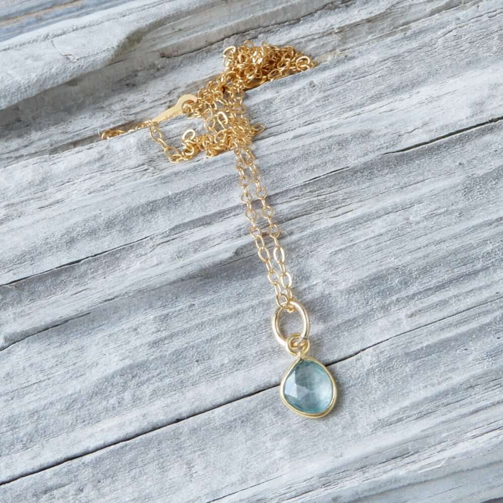 blue zircon gold necklace on wood background