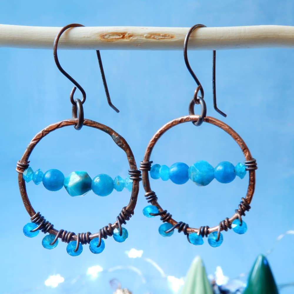 copper and blue apatite dangle hoop earrings on blue background