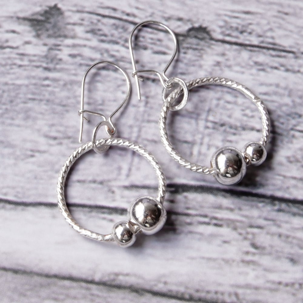 silver sensory fidget hoop earrings on wood background
